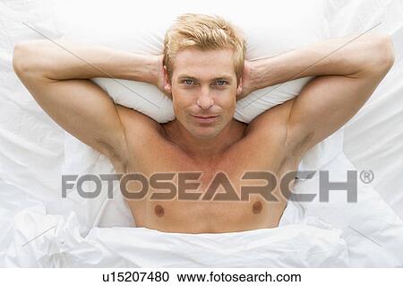Stock Image - Man lying in bed relaxing. Fotosearch