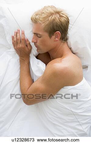 Stock Image - Man lying in bed sleeping. Fotosearch