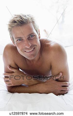 Man lying in bed smiling View Large Photo Image Picture - Man lying in bed smiling. Fotosearch