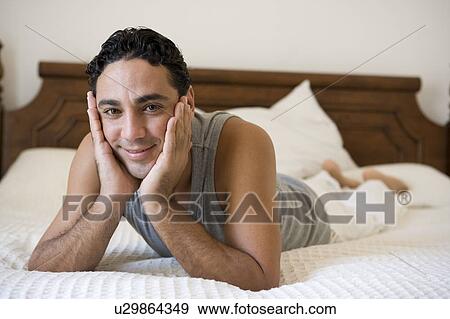 Man relaxing on bed in bedroom smiling (selective focus) View Large Photo Image Stock Photo - Man relaxing on bed in bedroom smiling (selective focus). Fotosearch