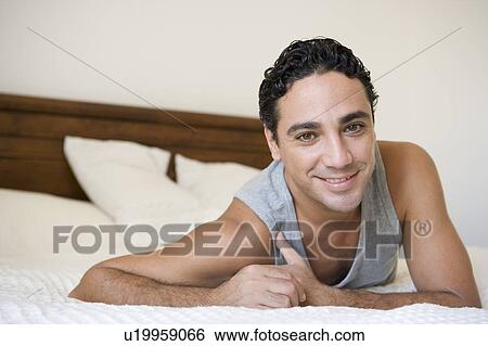 Man relaxing on bed in bedroom smiling (selective focus) View Large Photo Image Stock Photograph - Man relaxing on bed in bedroom smiling (selective focus). Fotosearch