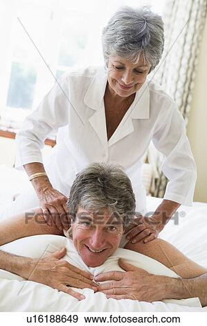 Stock Photo - Woman giving man massage in bedroom smiling. Fotosearch