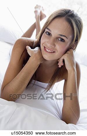 Stock Image - Woman lying in bed smiling. Fotosearch