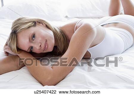 Stock Image - Woman lying in bed smiling. Fotosearch