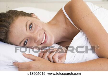Woman lying in bed smiling View Large Photo Image Stock Photo - Woman lying in bed smiling. Fotosearch