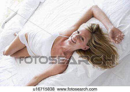 Stock Photo - Woman lying in bed smiling. Fotosearch