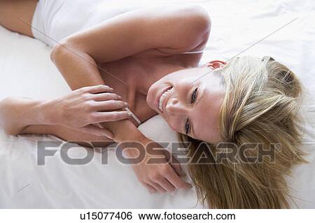 Woman lying in bed smiling View Large Photo Image Stock Photograph - Woman lying in bed smiling. Fotosearch