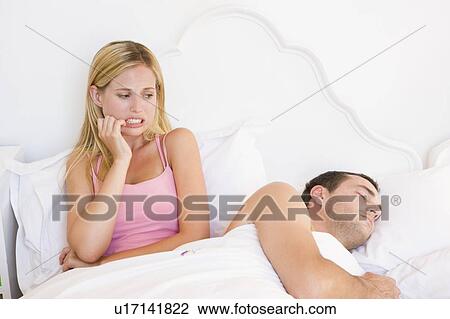 Stock Image - Young couple in bed having trouble sleeping. Fotosearch
