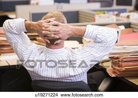 Businessman in cubicle with laptop and stacks of files View Large Photo Image Picture - Businessman in cubicle with laptop and stacks of files. Fotosearch