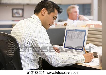 Businessman in cubicle with laptop writing View Large Photo Image Stock Photography - Businessman in cubicle with laptop writing. Fotosearch