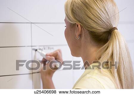 Businesswoman indoors writing on erasable board View Large Photo Image Stock Photo - Businesswoman indoors writing on erasable board. Fotosearch