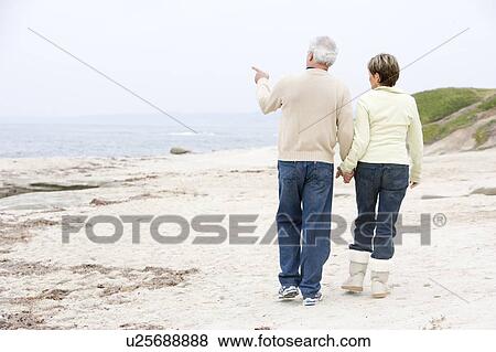 Stock Photo - Couple at the beach holding hands and pointing. Fotosearch