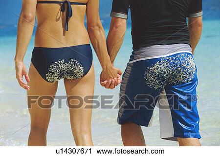 Stock Image - Couple holding hands at the beach (selective focus). Fotosearch