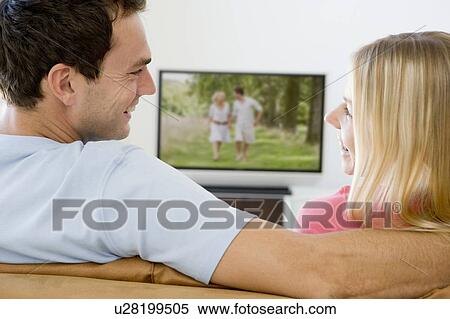 Couple in living room watching television smiling View Large Photo Image Stock Photography - Couple in living room watching television smiling. Fotosearch