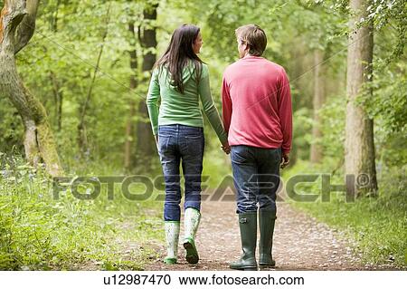 Stock Image - Couple walking on path holding hands. Fotosearch