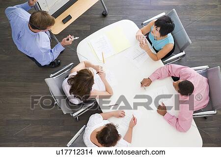 Picture - Four businesspeople at boardroom table watching presentation. Fotosearch