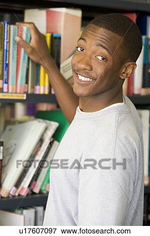 Man in library pulling book off shelf View Large Photo Image Stock Photo - Man in library pulling book off shelf. Fotosearch