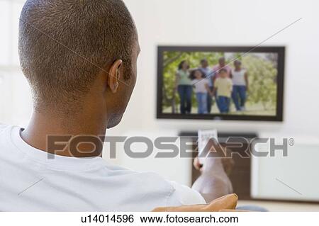 Stock Photograph - Man in living room watching television. Fotosearch