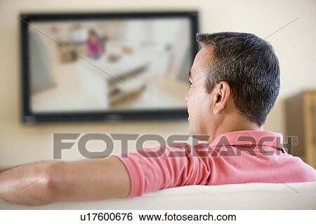 Man in living room watching television View Large Photo Image Stock Photograph - Man in living room watching television. Fotosearch