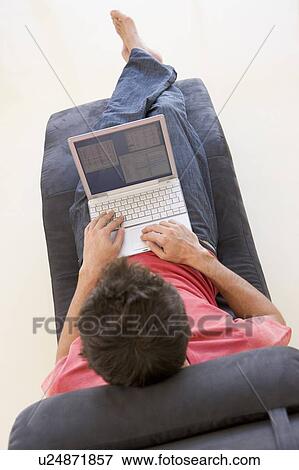 Stock Photo - Man sitting in chair using laptop. Fotosearch