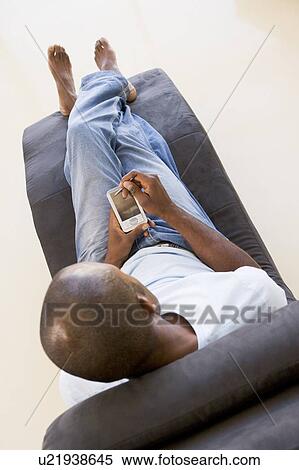 Man sitting in chair using personal digital assistant View Large Photo Image Stock Photography - Man sitting in chair using personal digital assistant. Fotosearch