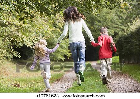 Stock Image - Mother and children running on path outdoors (rear view). Fotosearch