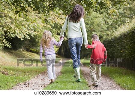 Stock Image - Mother and two young children walking on path outdoors (selective focus). Fotosearch