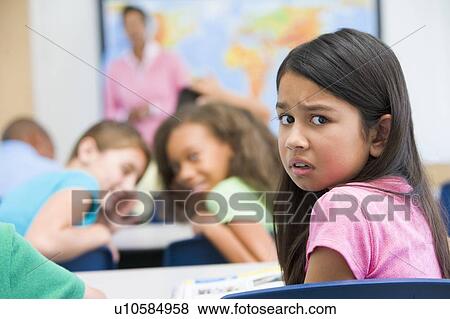 Stock Photo - Student in class being bullied by students in background (selective focus). Fotosearch