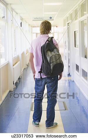 Stock Image - Student standing in corridor (selective focus). Fotosearch