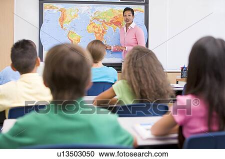 Stock Image - Students in class with teacher at front showing map (selective focus). Fotosearch