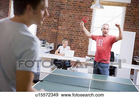 Stock Photo - Two men in office space playing ping pong. Fotosearch