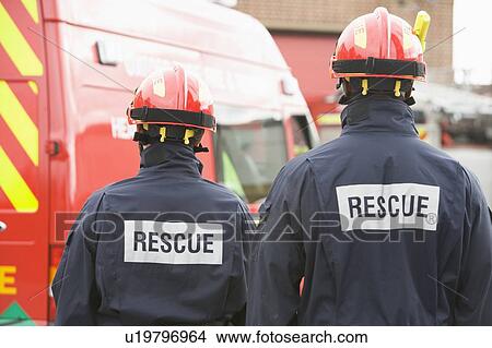 Two rescue workers standing near rescue vehicle View Large Photo Image Picture - Two rescue workers standing near rescue vehicle. Fotosearch