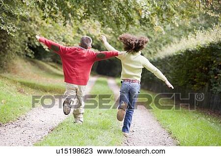 Stock Image - Two young friends running on a path outdoors. Fotosearch