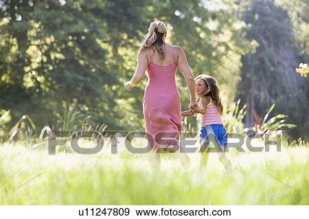 Woman and young girl running outdoors holding hands and smiling View Large Photo Image Stock Photo - Woman and young girl running outdoors holding hands and smiling. Fotosearch