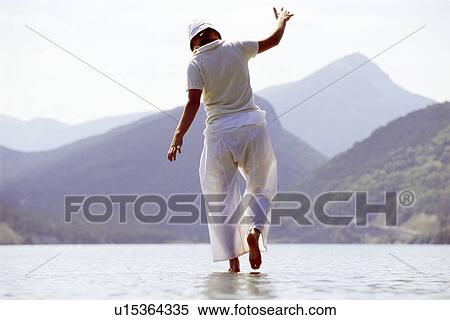 Stock Photography - Woman outdoors walking on water in scenic location. Fotosearch