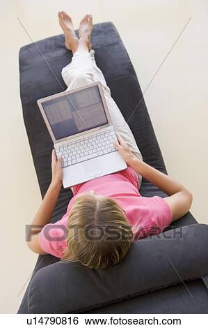 Stock Photograph - Woman sitting in chair using laptop. Fotosearch