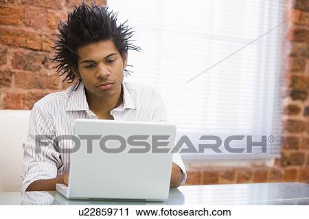 Stock Image - Businessman in office typing on laptop. Fotosearch