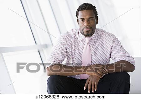 Businessman sitting in office lobby View Large Photo Image Stock Photo - Businessman sitting in office lobby. Fotosearch