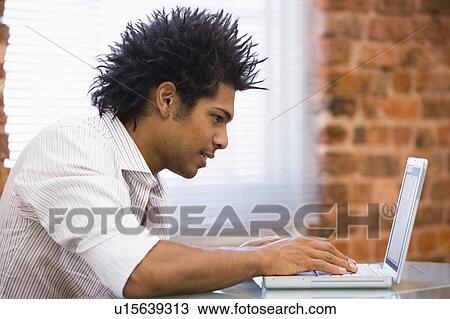 Stock Image - Businessman sitting in office typing on laptop. Fotosearch