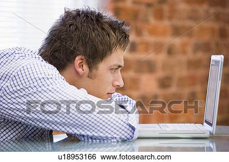 Businessman sitting in office with laptop View Large Photo Image Stock Photograph - Businessman sitting in office with laptop. Fotosearch