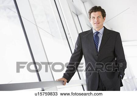 Businessman standing in corridor smiling View Large Photo Image Stock Image - Businessman standing in corridor smiling. Fotosearch
