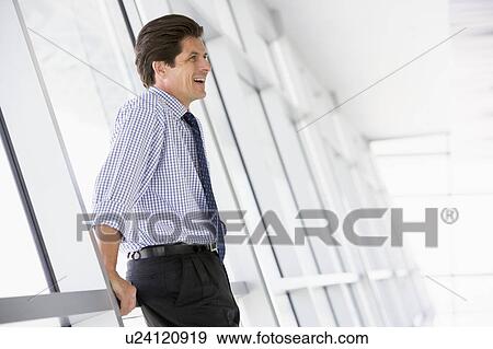 Stock Photo - Businessman standing in corridor laughing. Fotosearch