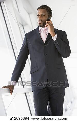Businessman standing in corridor using cellular phone View Large Photo Image Picture - Businessman standing in corridor using cellular phone. Fotosearch