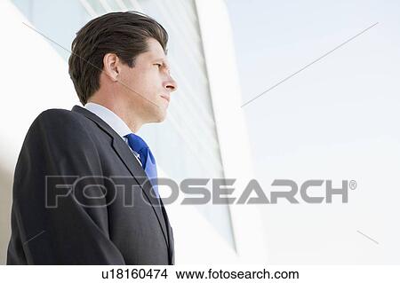 Picture - Businessman standing outdoors by building. Fotosearch