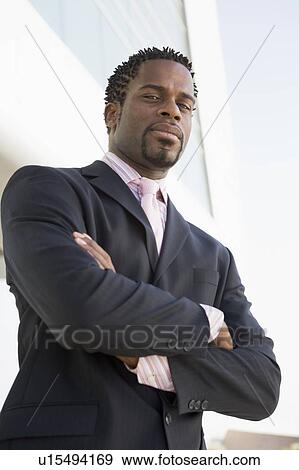 Businessman standing outdoors by building View Large Photo Image Stock Photo - Businessman standing outdoors by building. Fotosearch