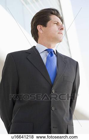 Businessman standing outdoors by building View Large Photo Image Stock Photo - Businessman standing outdoors by building. Fotosearch