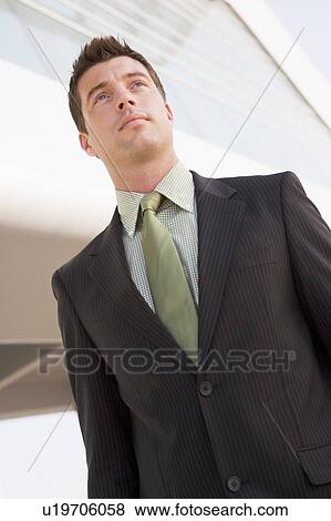 Stock Photo - Businessman standing outdoors by building. Fotosearch