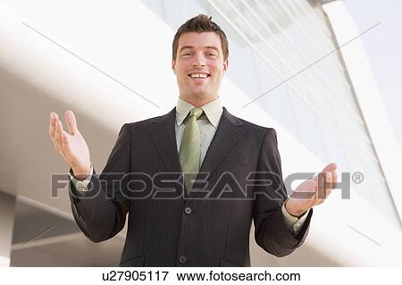 Businessman standing outdoors by building with hands out View Large Photo Image Stock Photo - Businessman standing outdoors by building with hands out. Fotosearch
