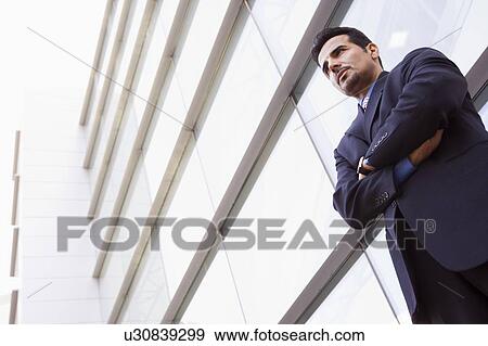 Stock Photo - Businessman standing outdoors by building (high key/selective focus). Fotosearch
