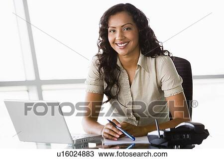 Businesswoman in office with laptop smiling (high key/selective focus) View Large Photo Image Stock Image - Businesswoman in office with laptop smiling (high key/selective focus). Fotosearch
